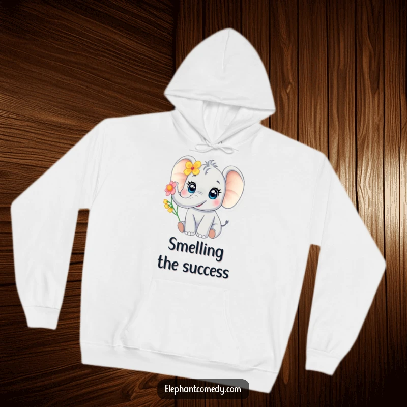 Funny baby elephant hoodie featuring a large-eyed elephant joyfully trumpeting with a flower, embodying warmth and adorableness.